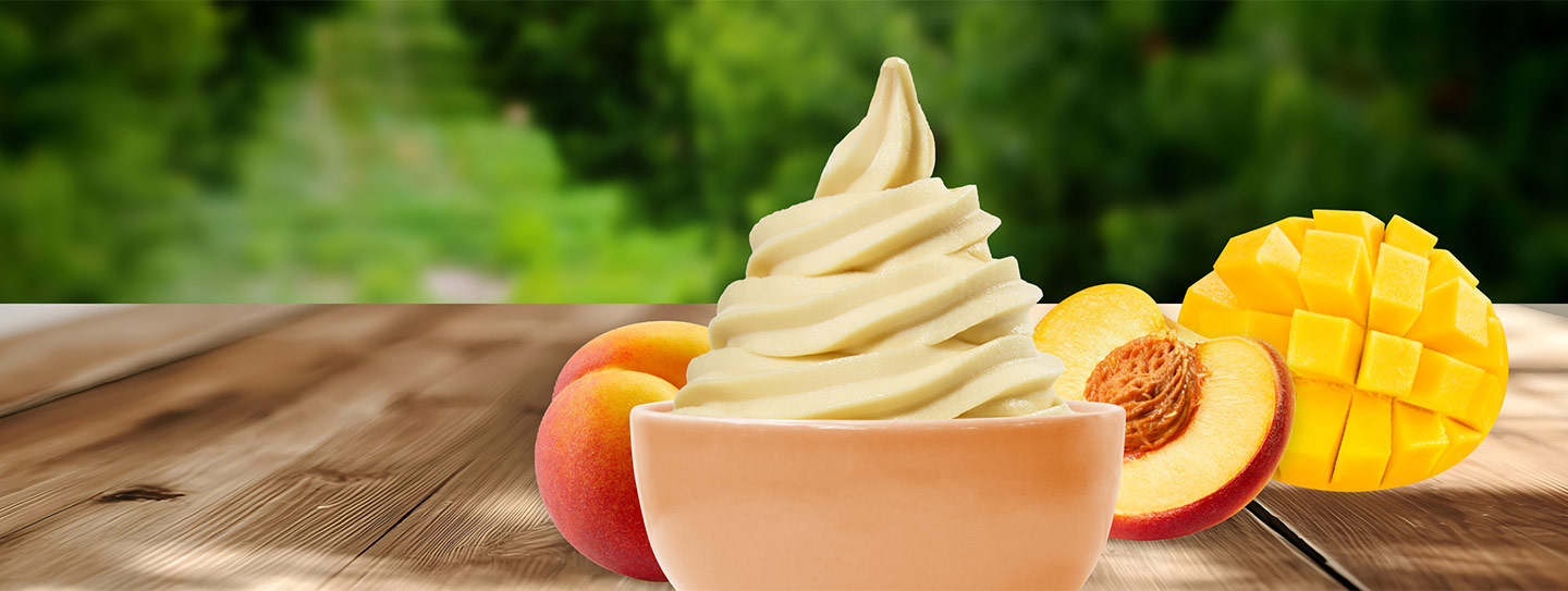 A cup of frozen yogurt alongside peaches and mango.