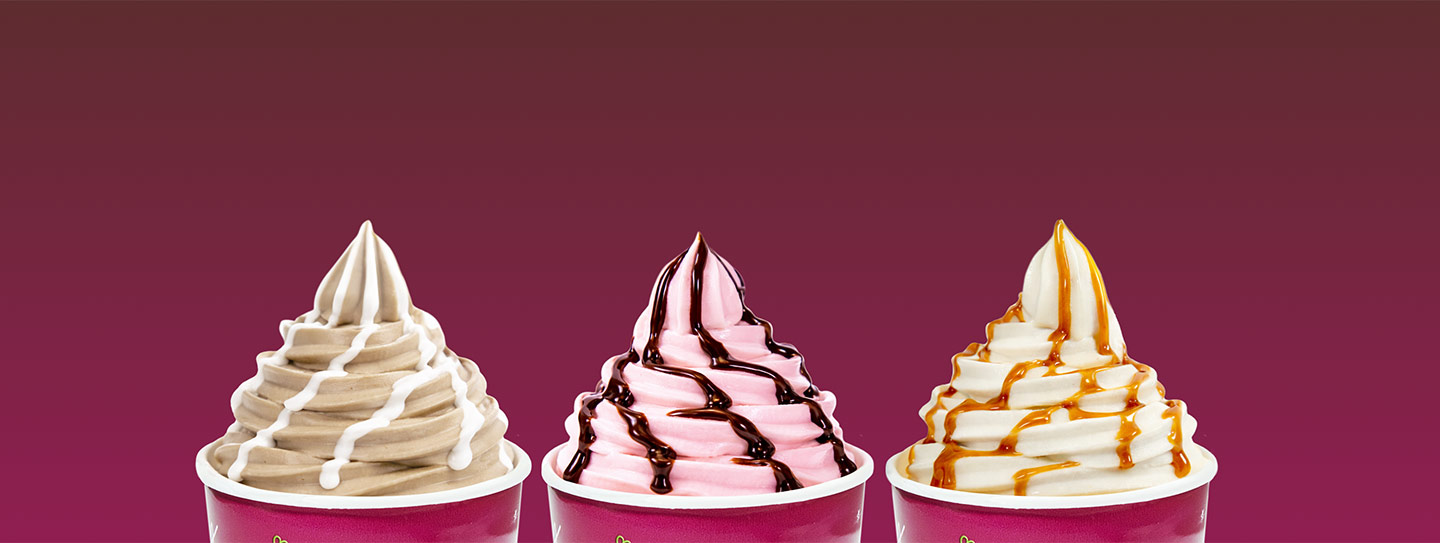 A group of Yogurtland cups of frozen yogurt with sauces